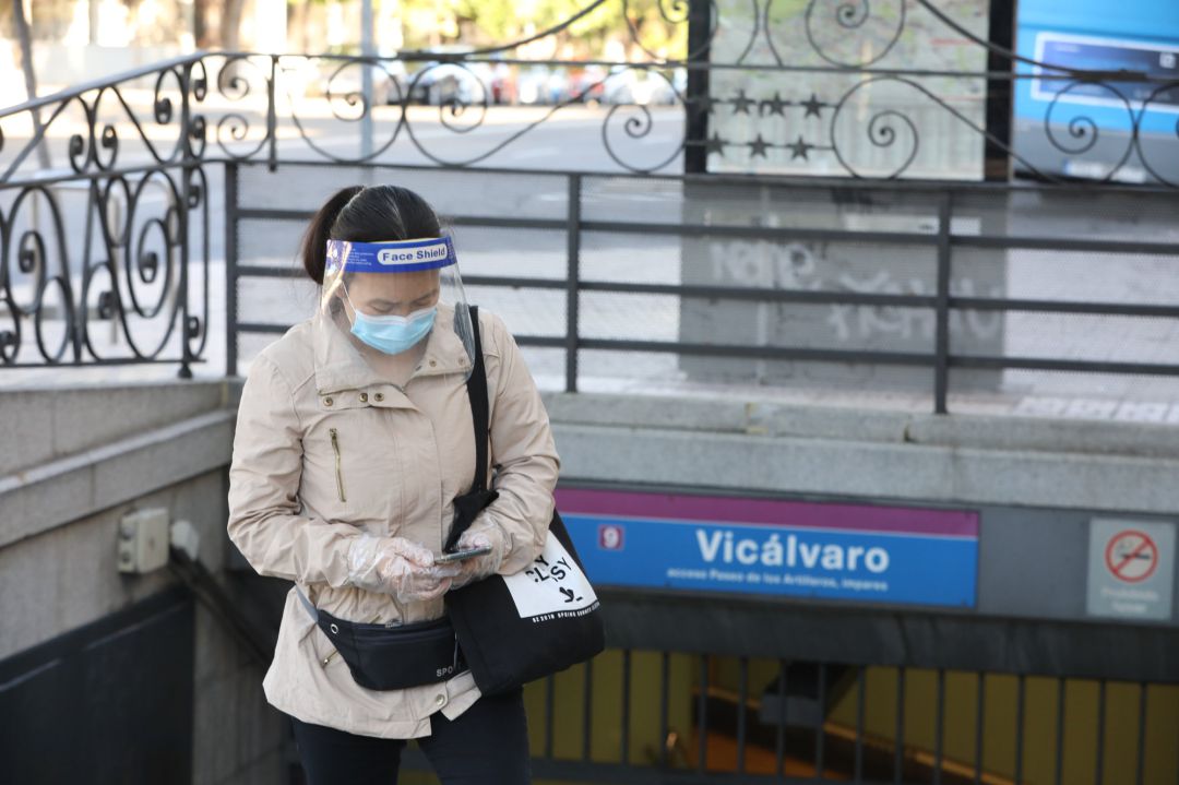 Una mujer protegida con mascarilla y pantalla protectora espera en la entrada al metro de Vicálvaro, en Madrid. Una mujer protegida con mascarilla y pantalla protectora espera en la entrada al metro de Vicálvaro, en Madrid.