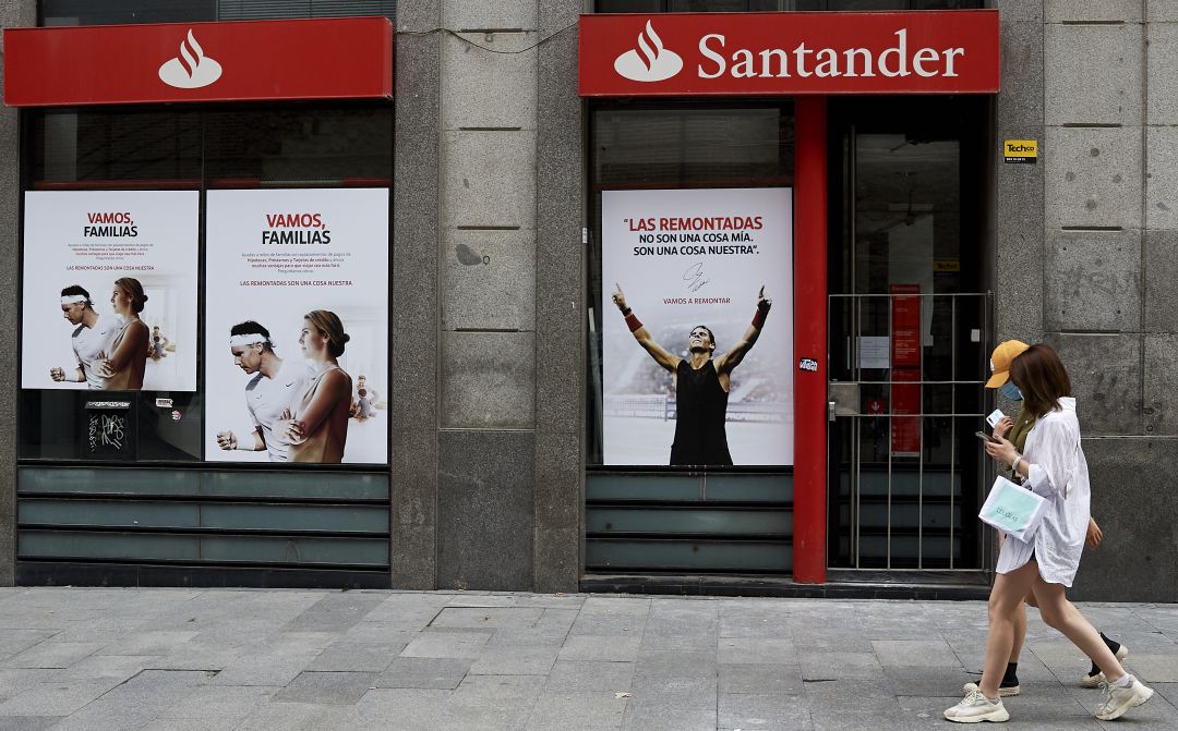 Dos mujeres pasean frente a una oficina del Banco Santander. Dos mujeres pasean frente a una oficina del Banco Santander.
