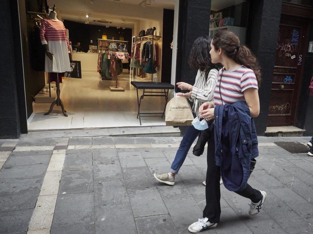 Dos jóvenes pasan por la puerta de una tienda de ropa, en una imagen de archivo Dos jóvenes pasan por la puerta de una tienda de ropa, en una imagen de archivo