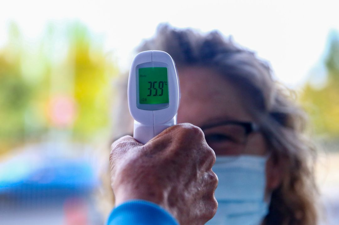 Un sanitario le toma la temperatura a una mujer antes de realizarle un test de antígenos Un sanitario le toma la temperatura a una mujer antes de realizarle un test de antígenos