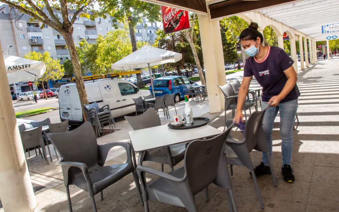 Una camarera limpia una de las mesas de la terraza del bar en el que trabaja Una camarera limpia una de las mesas de la terraza del bar en el que trabaja