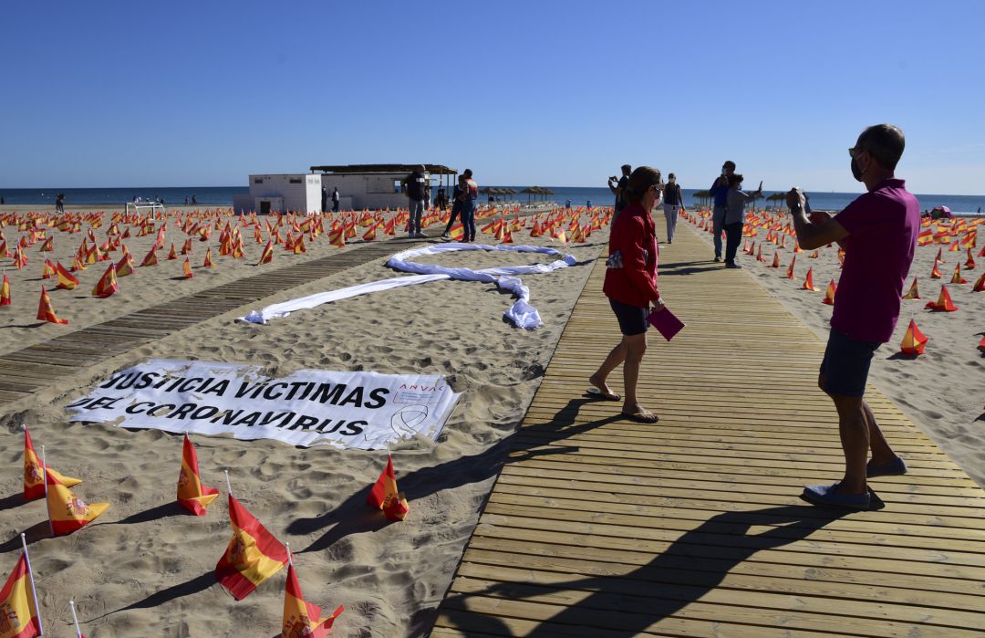 Varias personas visitan la Playa de la Patacona de Alboraia en la que se han colocado un total de 53.000 banderas de España en homenaje a los españoles fallecidos por coronavirus. Varias personas visitan la Playa de la Patacona de Alboraia en la que se han colocado un total de 53.000 banderas de España en homenaje a los españoles fallecidos por coronavirus.