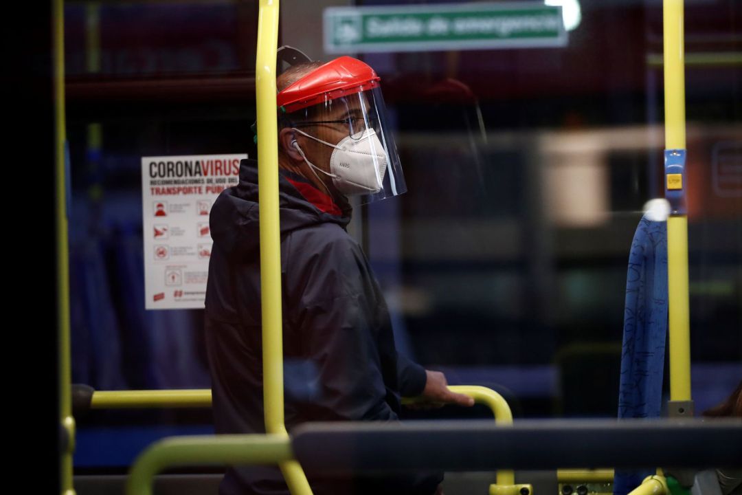 Un hombre protegido con mascarilla y una pantalla viaja en un autobús Un hombre protegido con mascarilla y una pantalla viaja en un autobús
