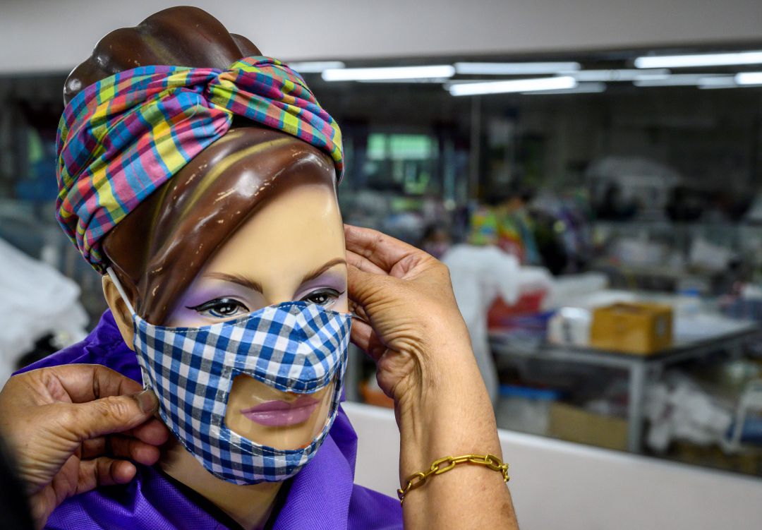 Una persona coloca una mascarilla transparente a un maniquí en una fábrica. Una persona coloca una mascarilla transparente a un maniquí en una fábrica.