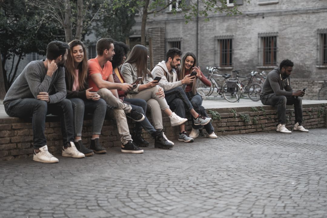 Grupo de personas relacionándose mientras otra se encuentra sola Grupo de personas relacionándose mientras otra se encuentra sola