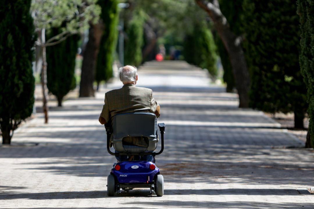Un anciano en silla de ruedas eléctrica Un anciano en silla de ruedas eléctrica