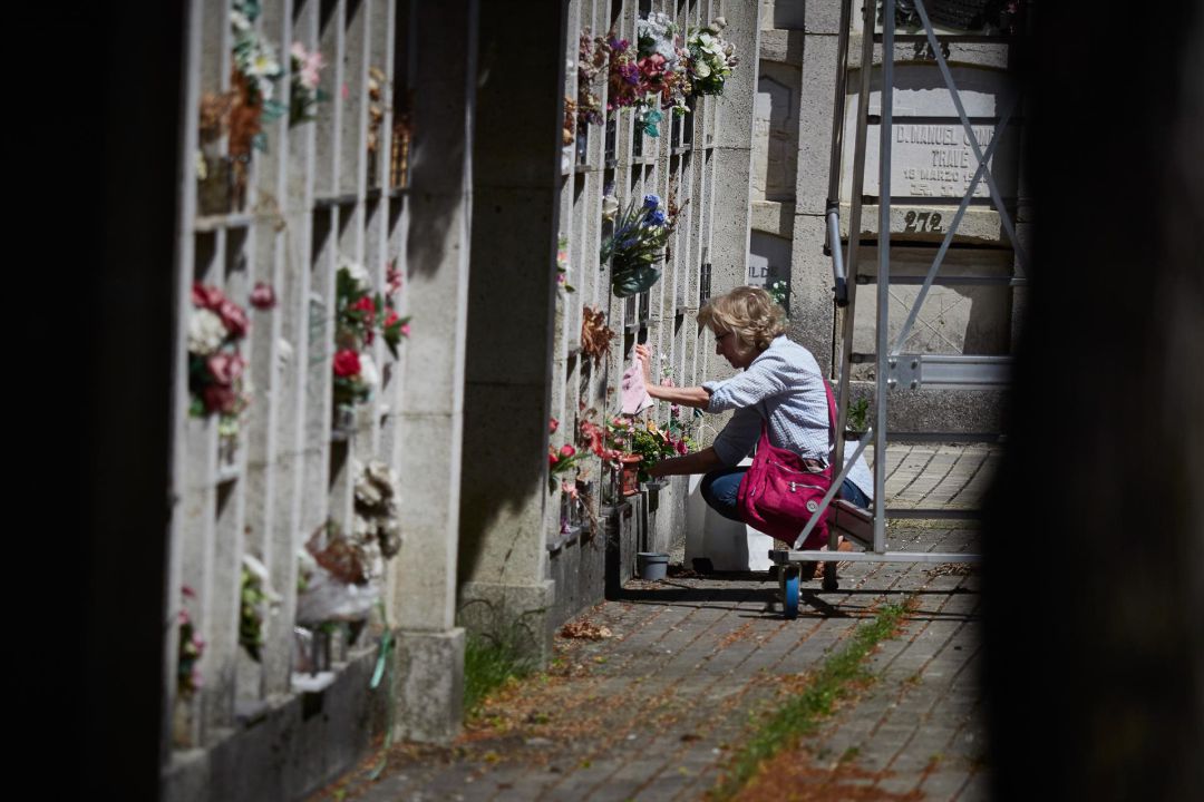 Una mujer deposita flores en un cementerio. Una mujer deposita flores en un cementerio.