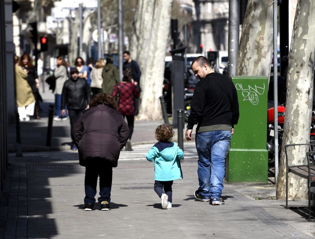 Unos padres pasean junto a su hija por la calle Unos padres pasean junto a su hija por la calle