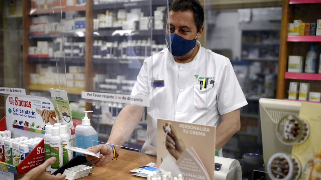 Un farmacéutico entrega una mascarilla a un cliente. Un farmacéutico entrega una mascarilla a un cliente.