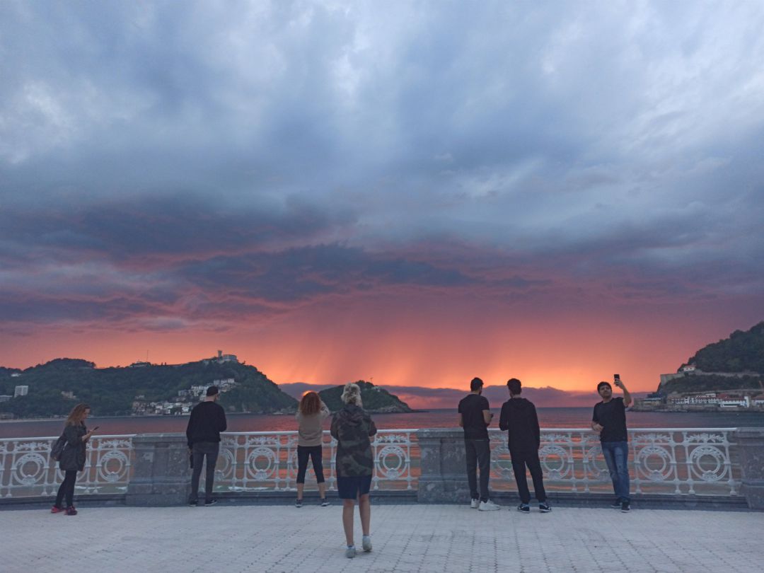 Unos turistas fotografían un atardecer en San Sebastián, en una imagen de archivo Unos turistas fotografían un atardecer en San Sebastián, en una imagen de archivo