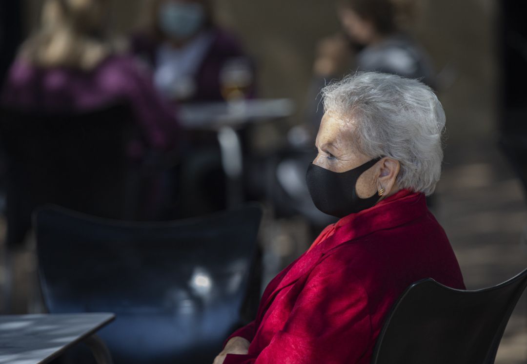 Una mujer mayor con mascarilla en la terraza de un bar. Una mujer mayor con mascarilla en la terraza de un bar.