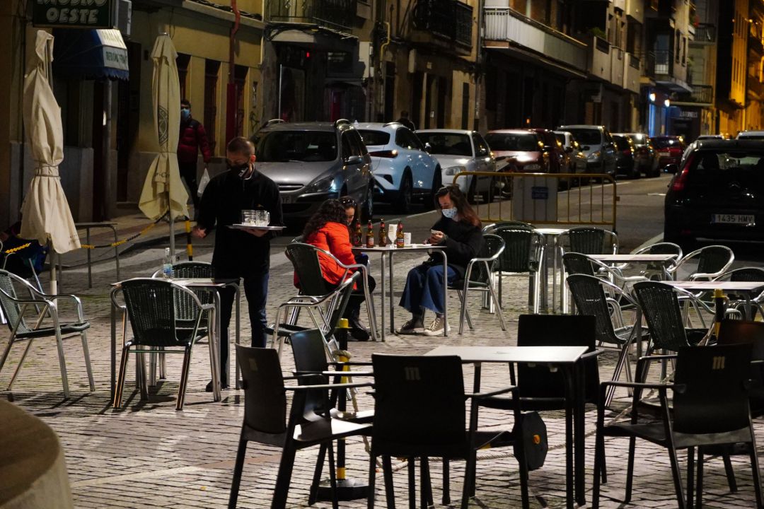 Un camarero trabaja en la terraza de un bar donde tres chicas consumen unas bebidas en Salamanca Un camarero trabaja en la terraza de un bar donde tres chicas consumen unas bebidas en Salamanca