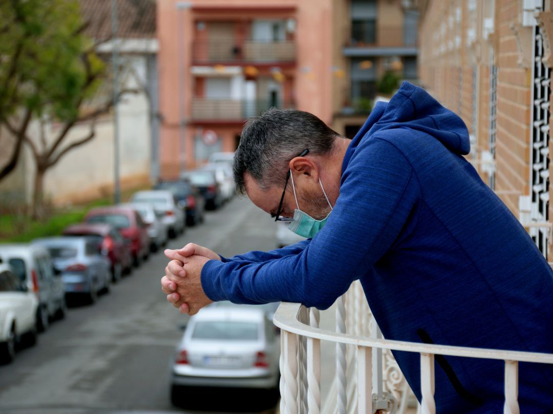 Un hombre con mascarilla en la terraza de una vivienda Un hombre con mascarilla en la terraza de una vivienda