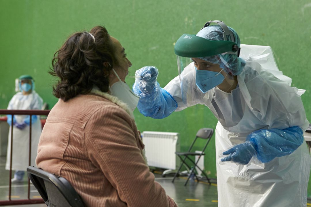 Un sanitario toma muestras a una mujer para realizar una PCR Un sanitario toma muestras a una mujer para realizar una PCR