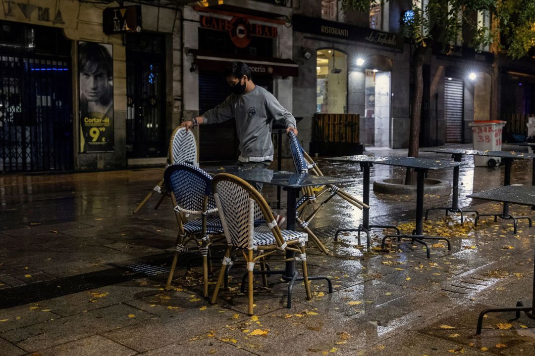 Un camarero recoge la terraza de su negocio en la primera jornada de toque de queda en Madrid Un camarero recoge la terraza de su negocio en la primera jornada de toque de queda en Madrid