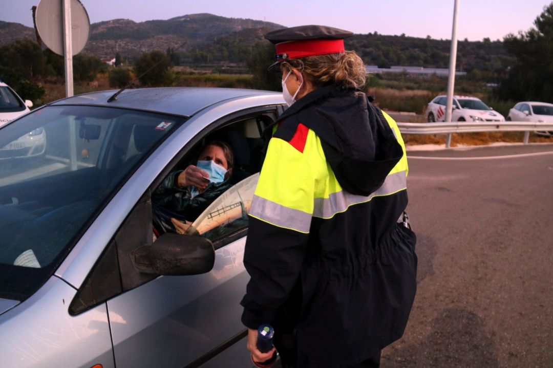 Pla mitjà d'una agent dels Mossos comprovant la identitat d'una conductora en els controls de mobilitat que s'han fet a Alcanar. Pla mitjà d'una agent dels Mossos comprovant la identitat d'una conductora en els controls de mobilitat que s'han fet a Alcanar.