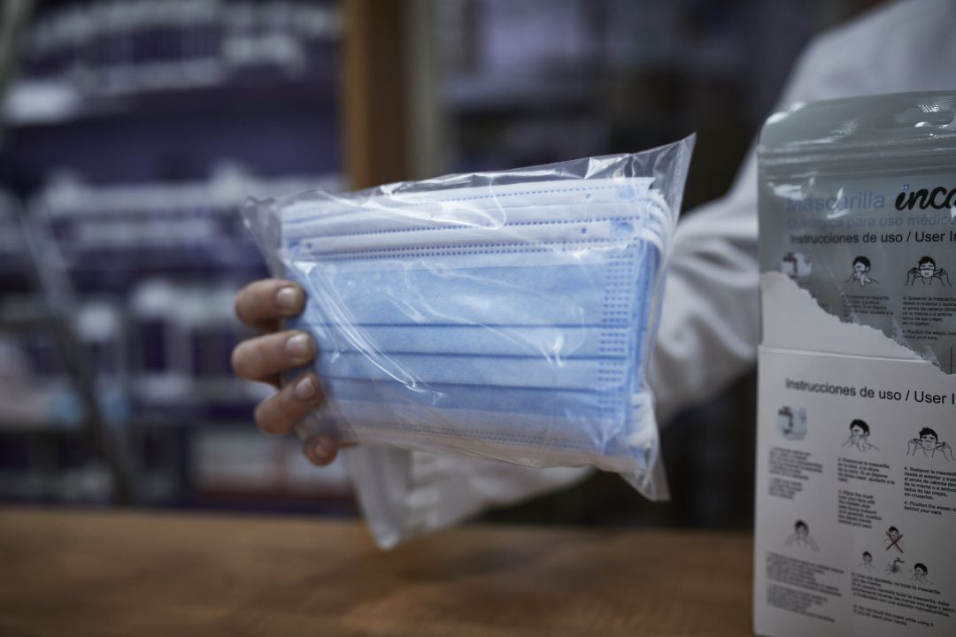 Una farmacéutica enseña a un cliente un paquete de mascarillas Una farmacéutica enseña a un cliente un paquete de mascarillas