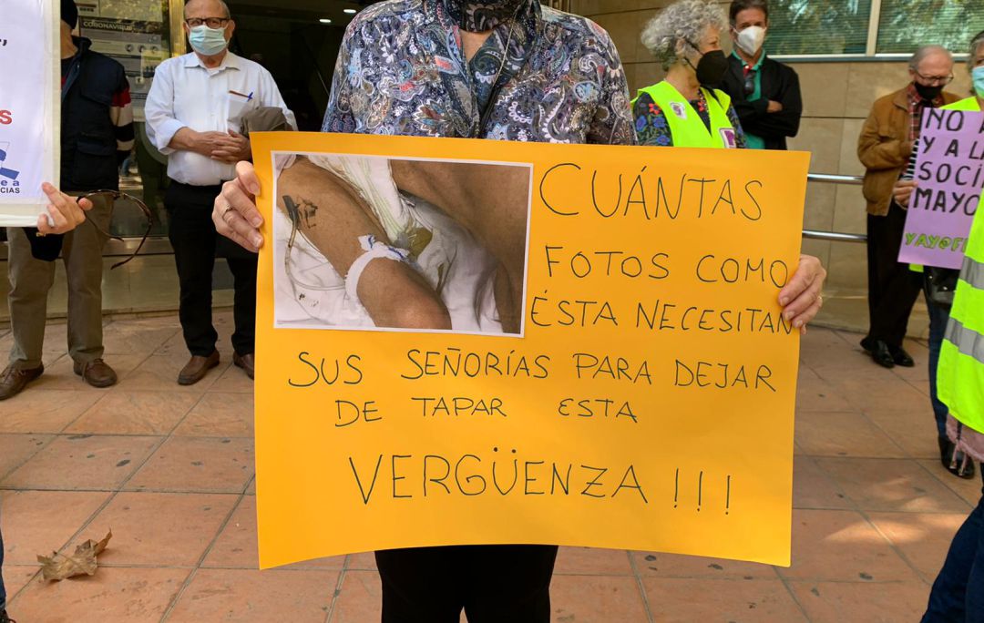 Familiar de un residente muestra una pancarta con una foto donde queda claro la precariedad con la que trabajan las TECAE por falta de medios y personal, mostrando su malestar porque la Asamblea Regional no haya querido investigar lo que ocurre Familiar de un residente muestra una pancarta con una foto donde queda claro la precariedad con la que trabajan las TECAE por falta de medios y personal, mostrando su malestar porque la Asamblea Regional no haya querido investigar lo que ocurre