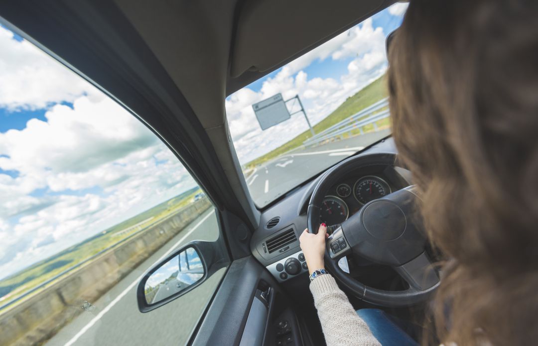 Una mujer conduce un vehículo por la carretera. Una mujer conduce un vehículo por la carretera.