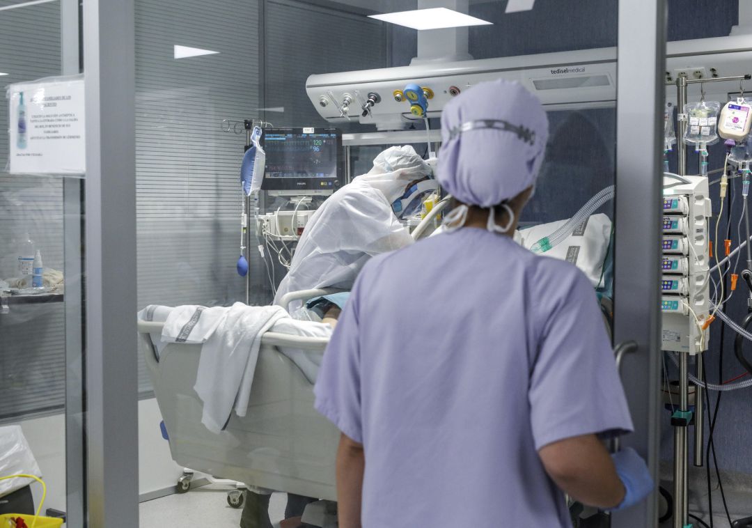 Trabajadores sanitarios totalmente protegidos atienden a un paciente con coronavirus ingresado en la UCI del Hospital Arnau de Vilanova, en Valencia Trabajadores sanitarios totalmente protegidos atienden a un paciente con coronavirus ingresado en la UCI del Hospital Arnau de Vilanova, en Valencia