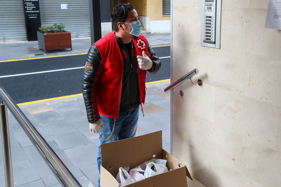 Un voluntario de Cruz Roja reparte comida a domicilio a personas vulnerables durante el confinamiento por la crisis sanitaria de coronavirus en València. Un voluntario de Cruz Roja reparte comida a domicilio a personas vulnerables durante el confinamiento por la crisis sanitaria de coronavirus en València.