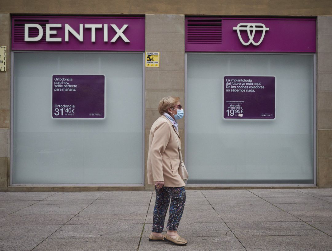 Una mujer paseas enfrente de una clínica de Dentix Una mujer paseas enfrente de una clínica de Dentix