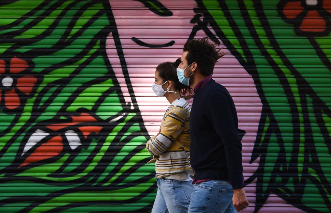Un hombre y una mujer pasean con la mascarilla puesta. Un hombre y una mujer pasean con la mascarilla puesta.