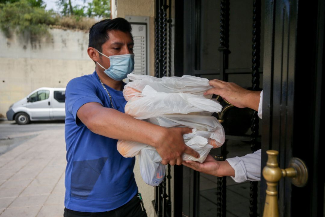 Una persona con mascarilla realiza una entrega a domicilio de alimentos en un programa solidario. Una persona con mascarilla realiza una entrega a domicilio de alimentos en un programa solidario.