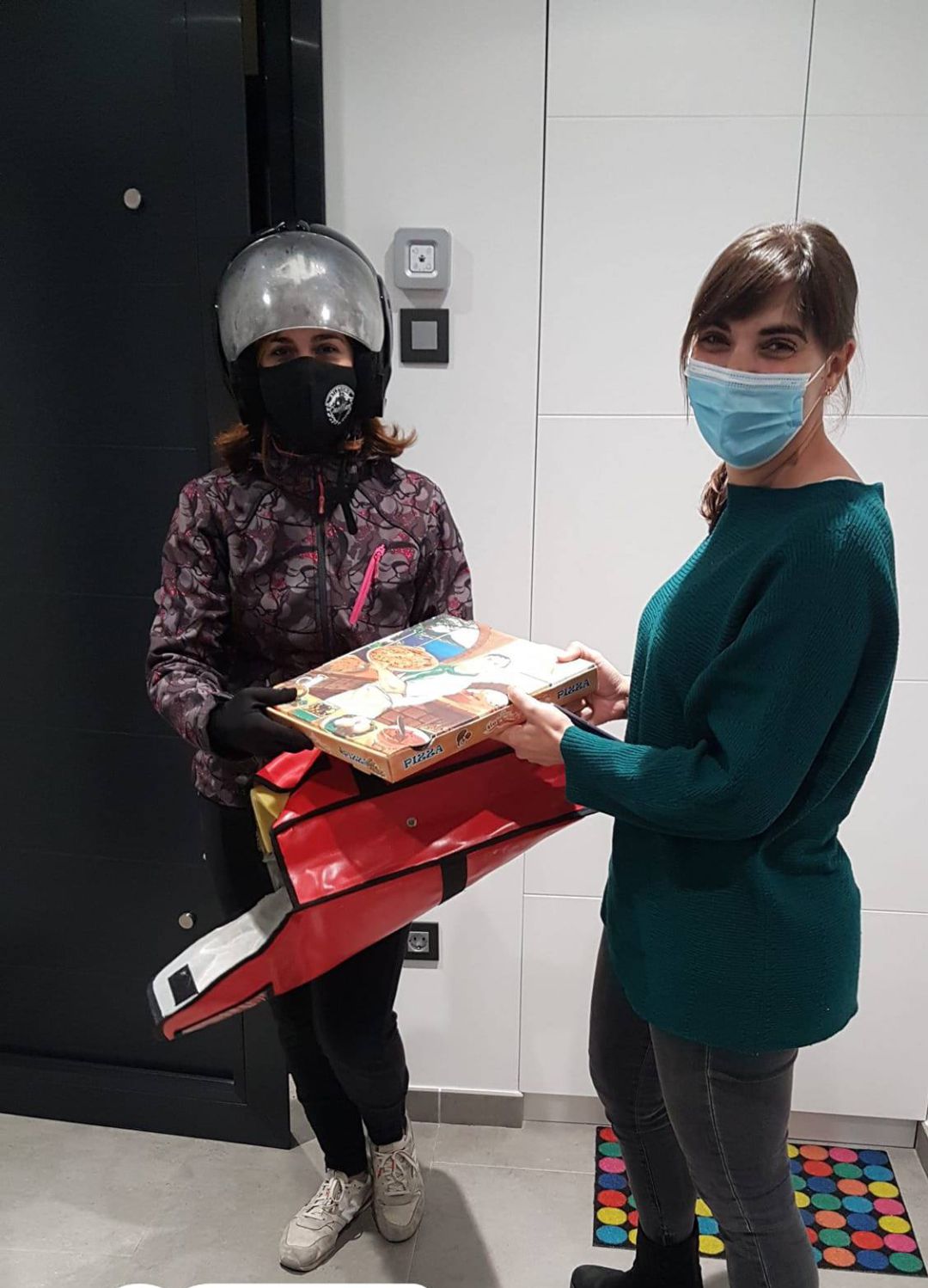 Lucía Arranz, con casco, entrega una pizza en casa de una vecina cuellarana Lucía Arranz, con casco, entrega una pizza en casa de una vecina cuellarana