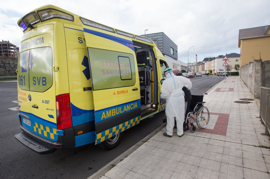 Un trabajador sanitario totalmente protegido ayuda a subir a la ambulancia a un anciano. Un trabajador sanitario totalmente protegido ayuda a subir a la ambulancia a un anciano.