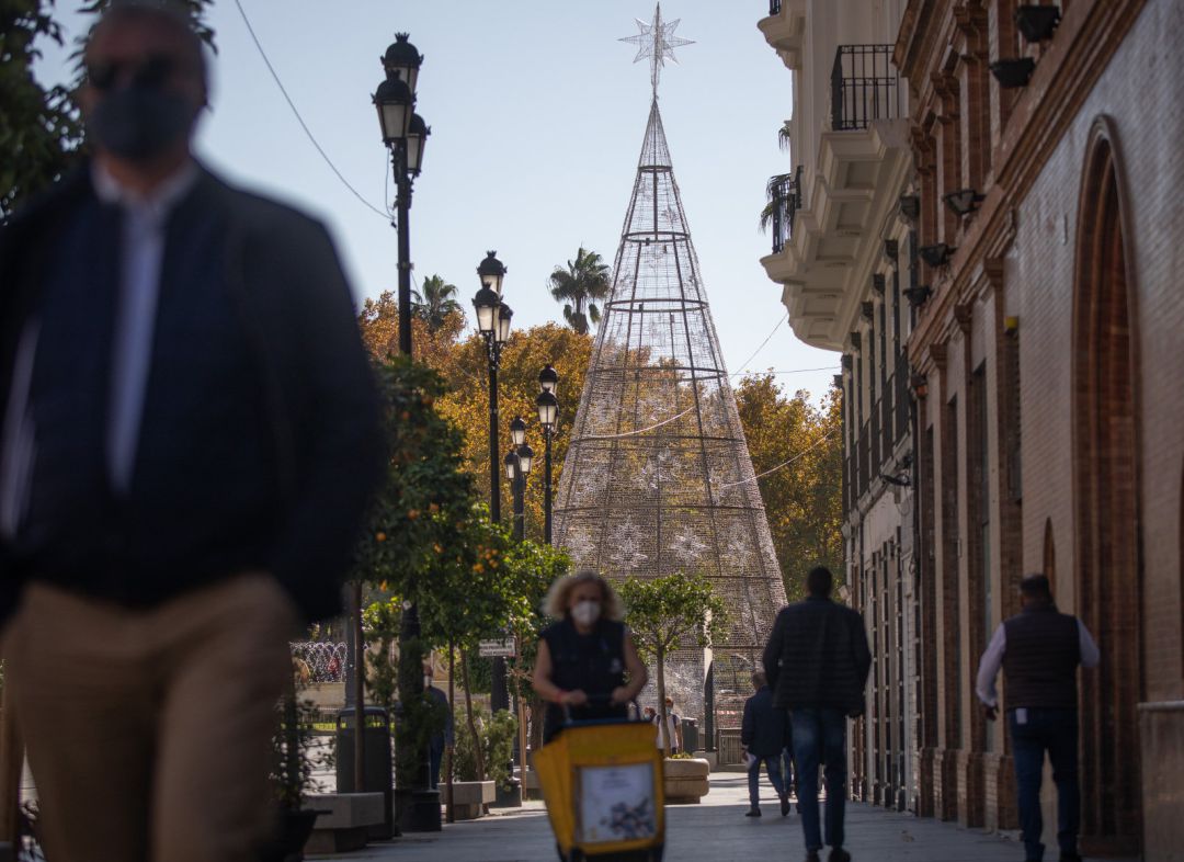 Transeúntes por la Puerta de Jerez en Sevilla, al lado del árbol de Navidad. Transeúntes por la Puerta de Jerez en Sevilla, al lado del árbol de Navidad.