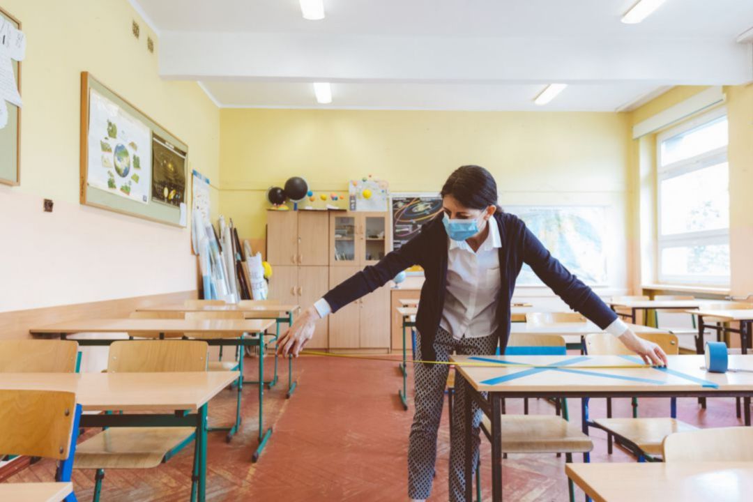 Una profesora toma medidas entre pupitres en un aula Una profesora toma medidas entre pupitres en un aula