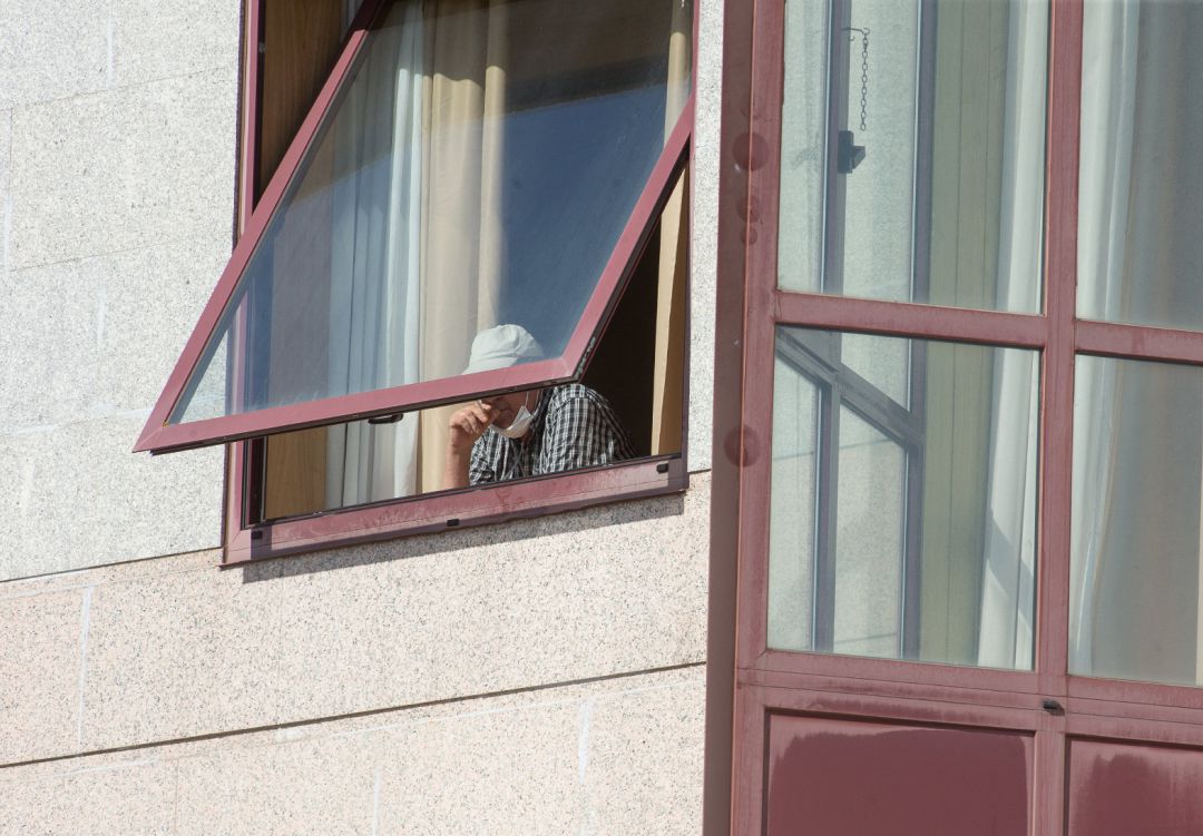 Una persona se asoma por la ventana de una residencia de mayores Una persona se asoma por la ventana de una residencia de mayores