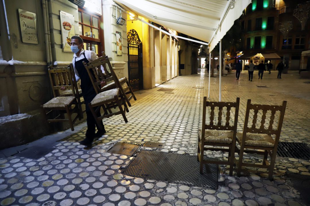 Un camarero se afanan en recogen la terraza del bar ubicado en el centro de la capital Un camarero se afanan en recogen la terraza del bar ubicado en el centro de la capital