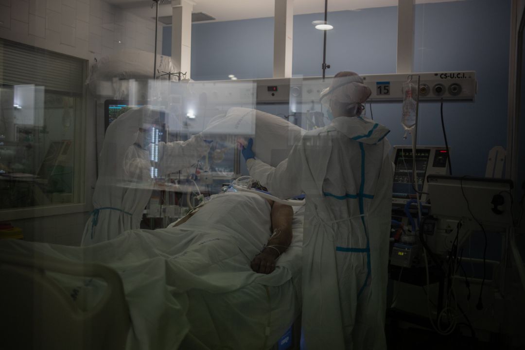 Trabajadores sanitarios protegidos atienden a un paciente en la UCI Trabajadores sanitarios protegidos atienden a un paciente en la UCI