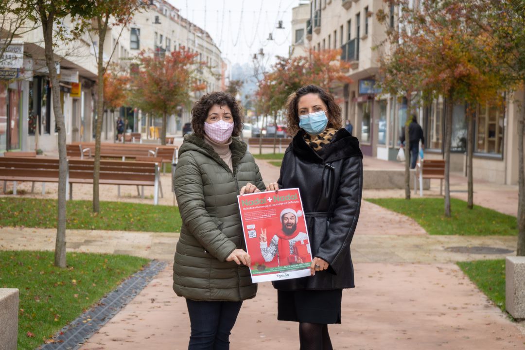 La alcaldesa de Tomiño, Sandra González (derecha), junto a la técnica de comercio del Concello sujetando el cartel de la campaña "Nadal + Nadal". La alcaldesa de Tomiño, Sandra González (derecha), junto a la técnica de comercio del Concello sujetando el cartel de la campaña "Nadal + Nadal".