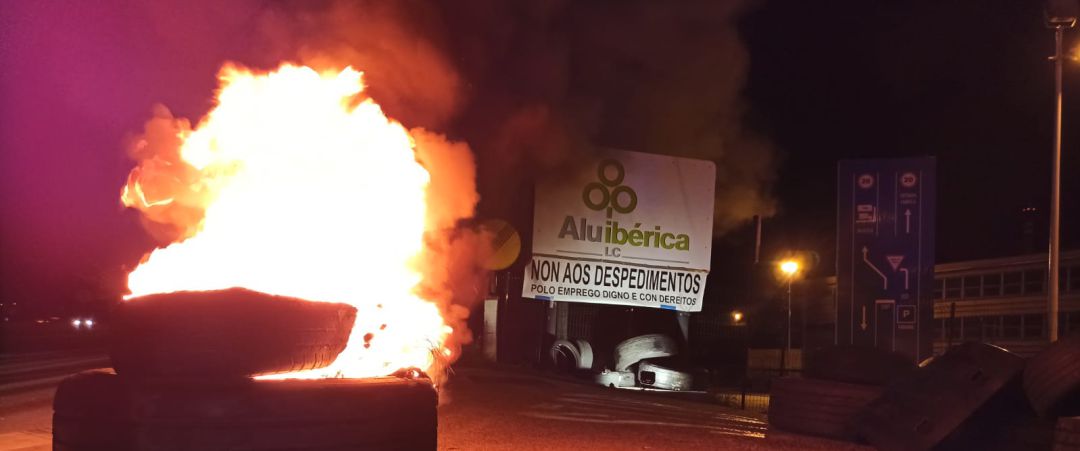 Un neumático ardiendo ante la sede de Alu Ibérica en la primera jornada de huelga Un neumático ardiendo ante la sede de Alu Ibérica en la primera jornada de huelga