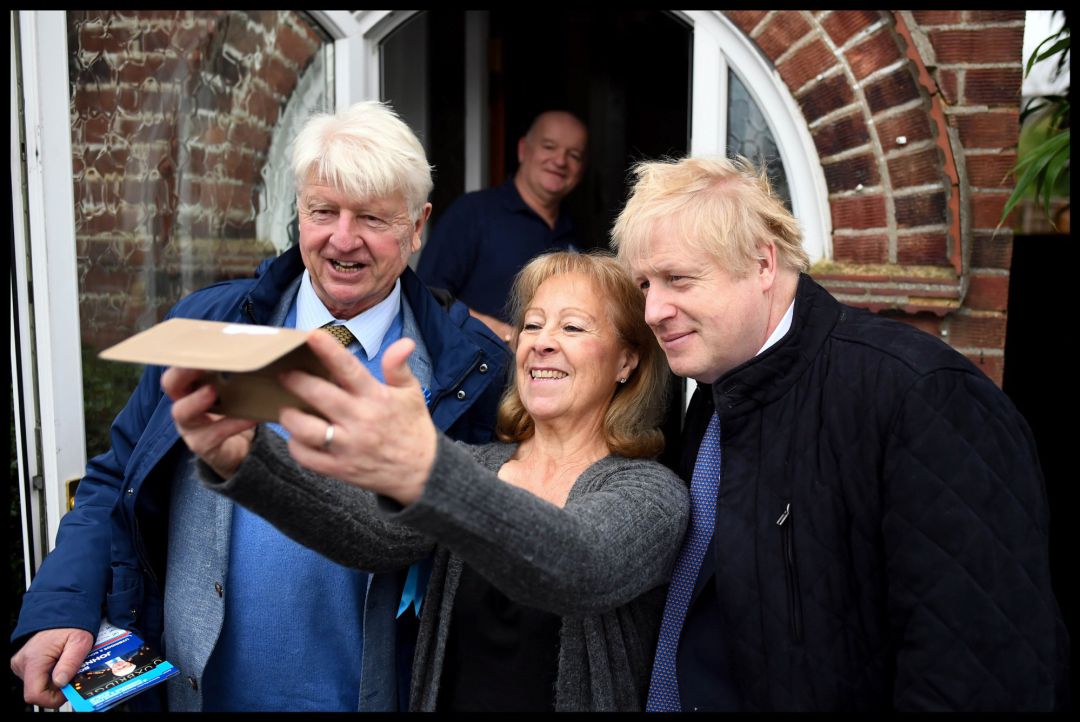 Boris Johnson junto a su padre, Stanley, se hacen una foto con una votante conservadora Boris Johnson junto a su padre, Stanley, se hacen una foto con una votante conservadora