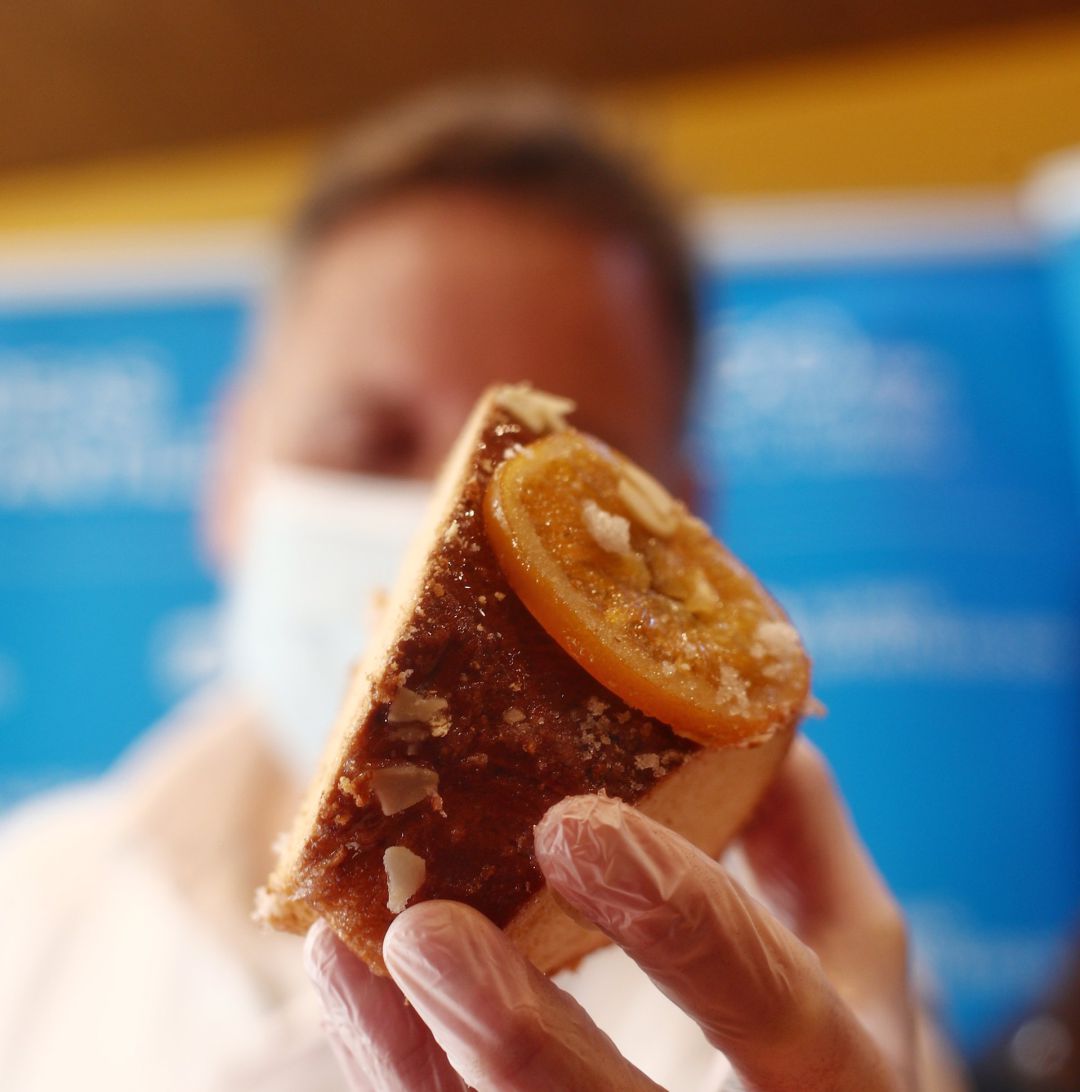 Un repostero sostiene un trozo de un roscón de reyes - Un repostero sostiene un trozo de un roscón de reyes -