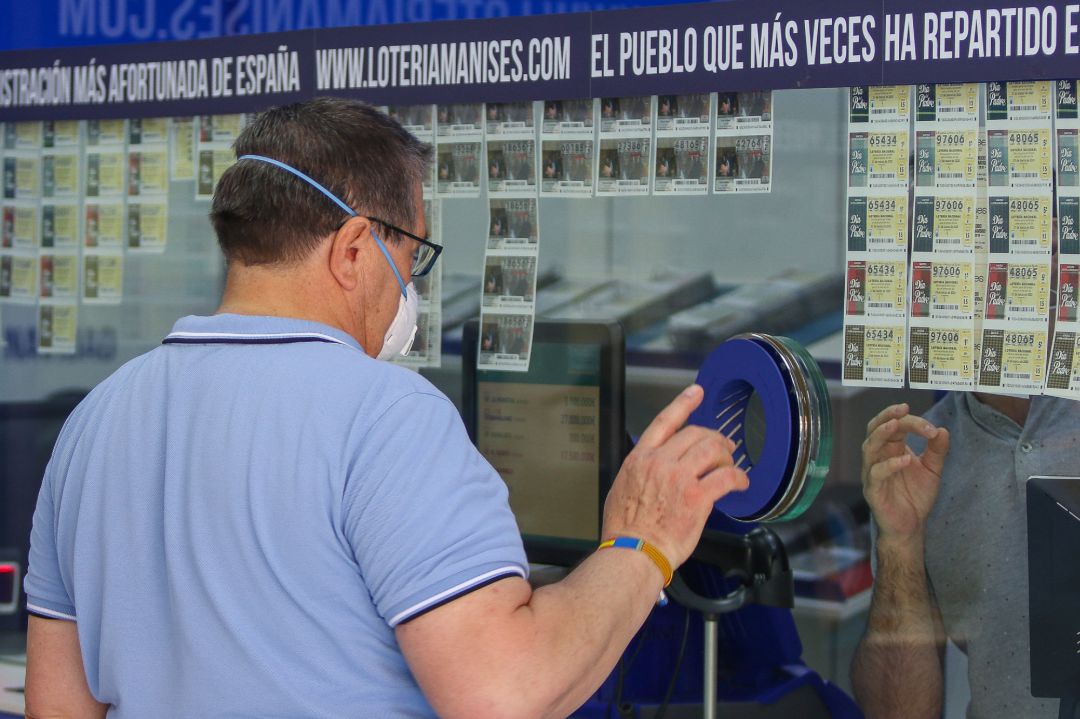 Un hombre compra lotería en una administración Un hombre compra lotería en una administración