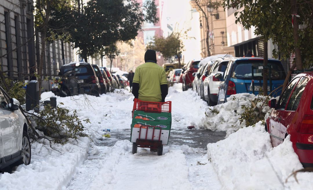 Un hombre arrastra una carretilla por una calle del centro aún con nieve y árboles caídos en Madrid (España). Un hombre arrastra una carretilla por una calle del centro aún con nieve y árboles caídos en Madrid (España).