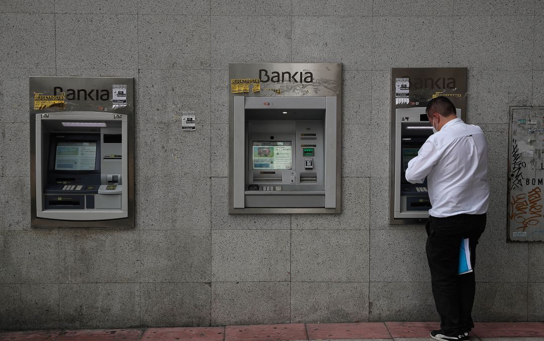 Un hombre saca dinero en un cajero. Un hombre saca dinero en un cajero.
