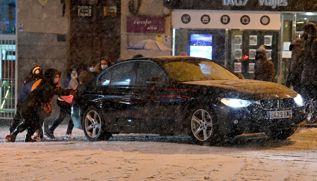 Varias personas empujan un vehículo durante una nevada. Varias personas empujan un vehículo durante una nevada.