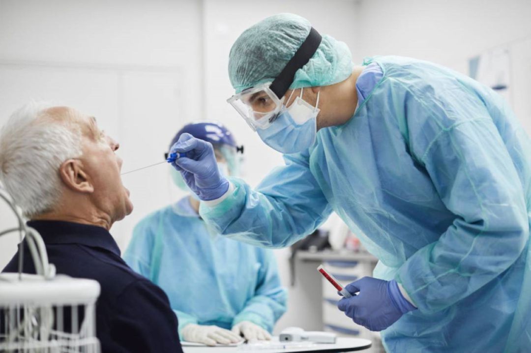 Un sanitario toma muestras a un paciente para una prueba PCR Un sanitario toma muestras a un paciente para una prueba PCR