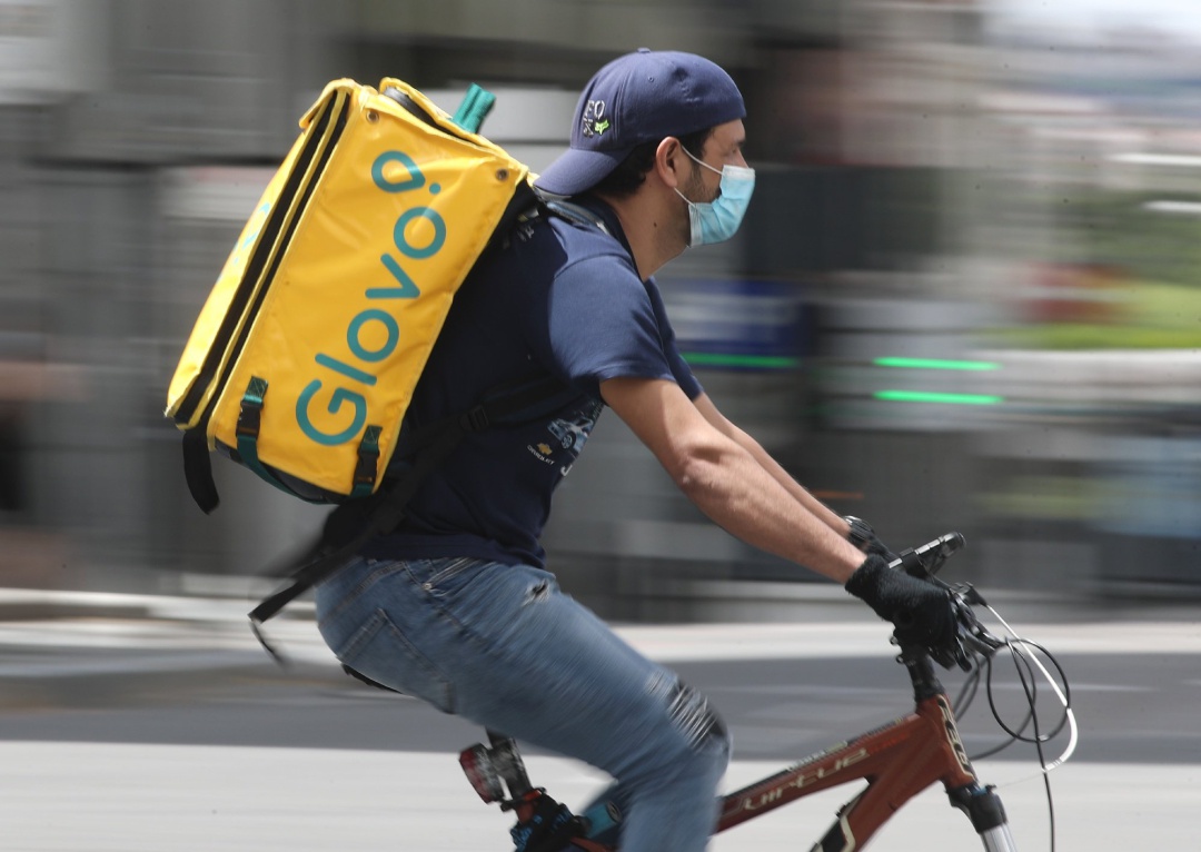 Un repartidor de Glovo monta una bicicleta durante su jornada laboral Un repartidor de Glovo monta una bicicleta durante su jornada laboral