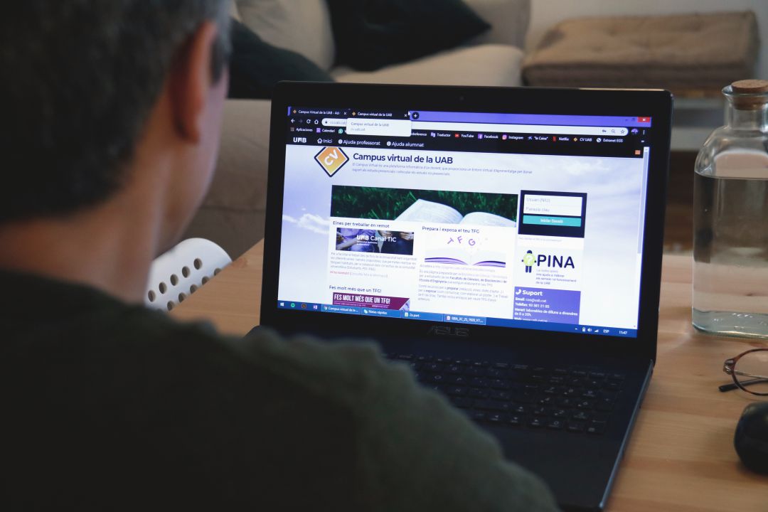 Un noi observa una pàgina web des del seu ordinador portàtil Un noi observa una pàgina web des del seu ordinador portàtil