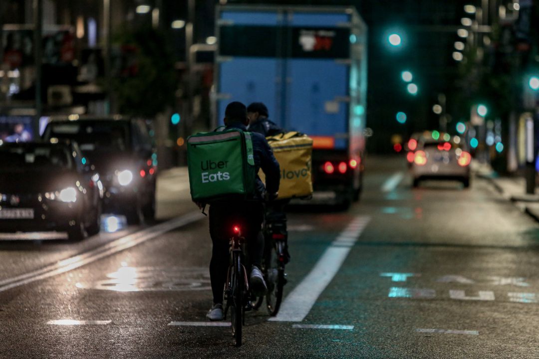 Un rider de Glovo y otro de Uber Eats. Un rider de Glovo y otro de Uber Eats.