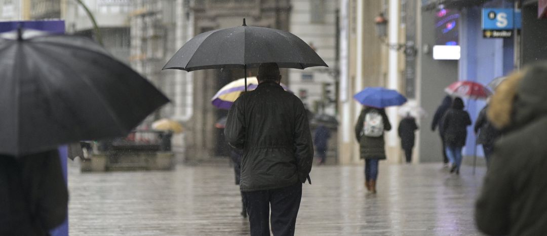 Transeúntes caminan protegidos por una vía de A Coruña Transeúntes caminan protegidos por una vía de A Coruña