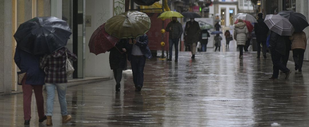 Transeúntes caminan protegidos por una vía de A Coruña Transeúntes caminan protegidos por una vía de A Coruña