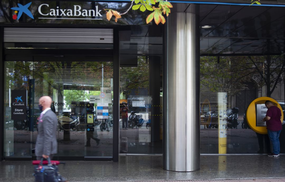 Varias personas frente a una sucursal de Caixabank. Varias personas frente a una sucursal de Caixabank.